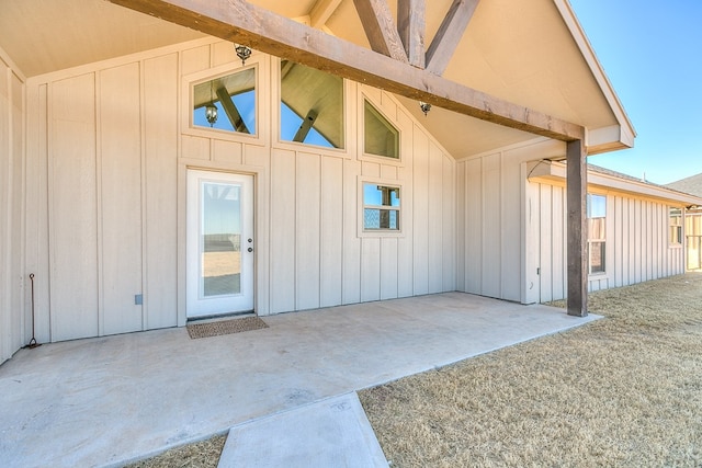 entrance to property with board and batten siding and a patio area