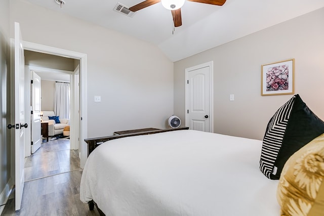 bedroom with ceiling fan, visible vents, wood finished floors, and vaulted ceiling