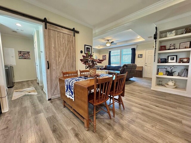 7754 S Copper Mountain Cir, San Angelo, TX 76901 - dining area featuring a barn door, crown molding, light wood-type flooring, a ceiling fan, and a raised ceiling