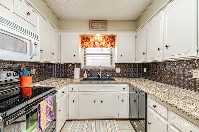 kitchen featuring electric range, a sink, white microwave, and white cabinets