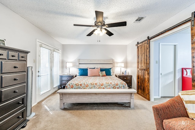 bedroom featuring light carpet, a barn door, visible vents, and ceiling fan