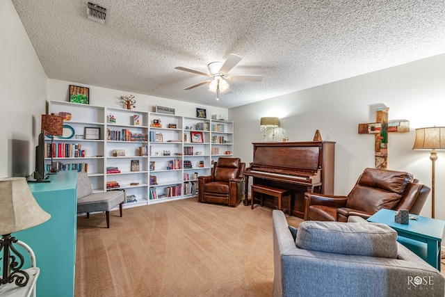 living area featuring carpet floors, visible vents, ceiling fan, and a textured ceiling