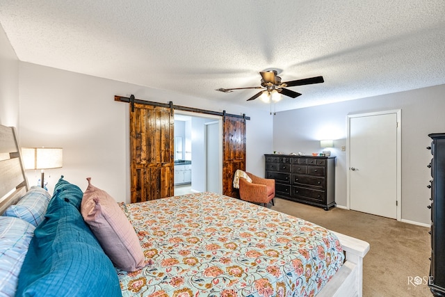 bedroom with light colored carpet, ceiling fan, a textured ceiling, and a barn door