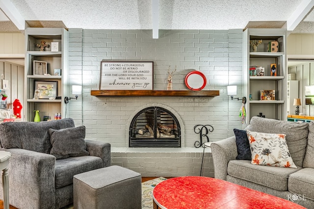 living area featuring built in shelves, beam ceiling, a fireplace, and a textured ceiling