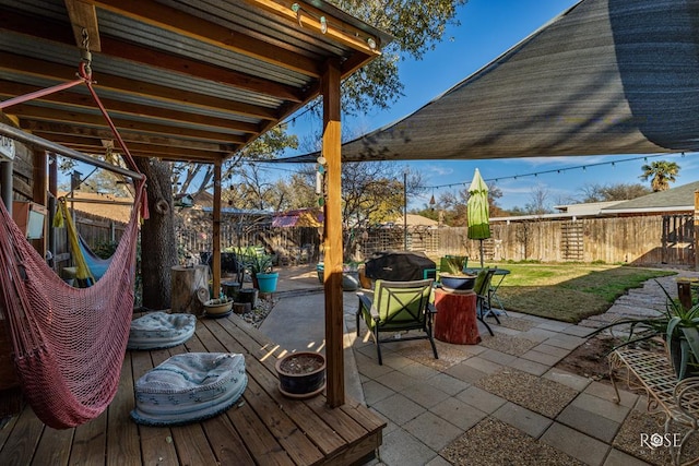 wooden deck with a patio area, a lawn, and a fenced backyard