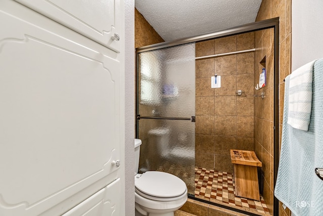 bathroom with a stall shower, a textured ceiling, and toilet