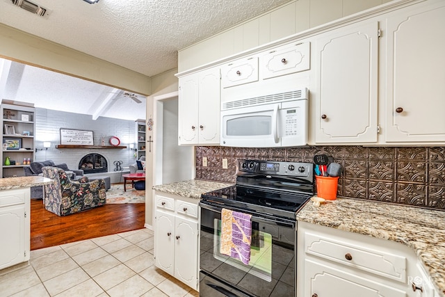 kitchen featuring light tile patterned floors, visible vents, electric range, white microwave, and white cabinetry