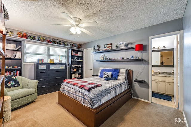 carpeted bedroom with baseboards, a ceiling fan, ensuite bathroom, a textured ceiling, and a sink