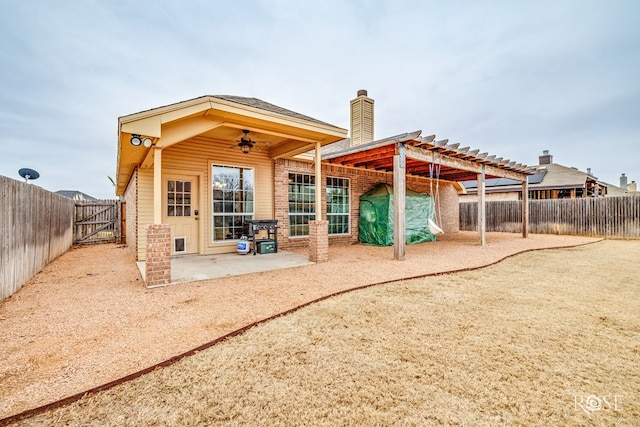 back of property with a chimney, a patio area, brick siding, and a fenced backyard