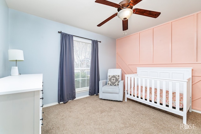 bedroom featuring light carpet, ceiling fan, and a crib