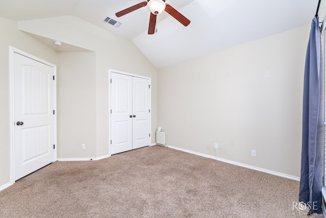 unfurnished bedroom with baseboards, visible vents, lofted ceiling, carpet, and a closet