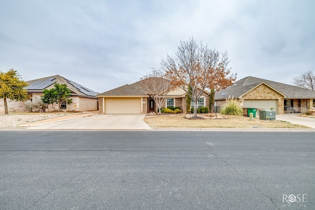 single story home with driveway, a garage, solar panels, and brick siding