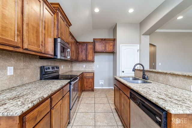 kitchen featuring appliances with stainless steel finishes, a sink, light stone countertops, and brown cabinets