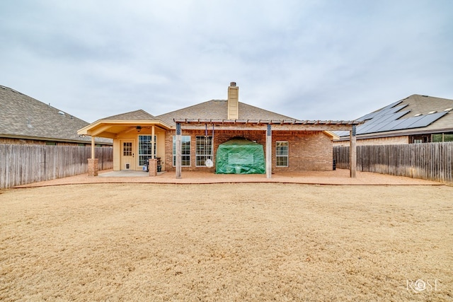 rear view of house featuring a fenced backyard, a patio, and a chimney