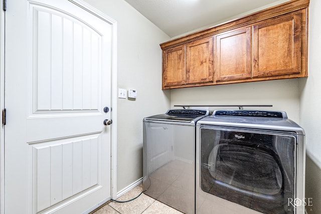 washroom with light tile patterned flooring, cabinet space, baseboards, and separate washer and dryer