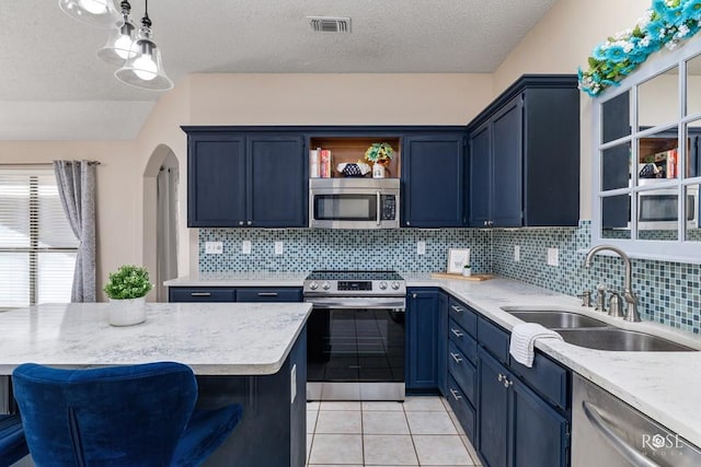 kitchen with sink, hanging light fixtures, light tile patterned floors, appliances with stainless steel finishes, and a kitchen breakfast bar