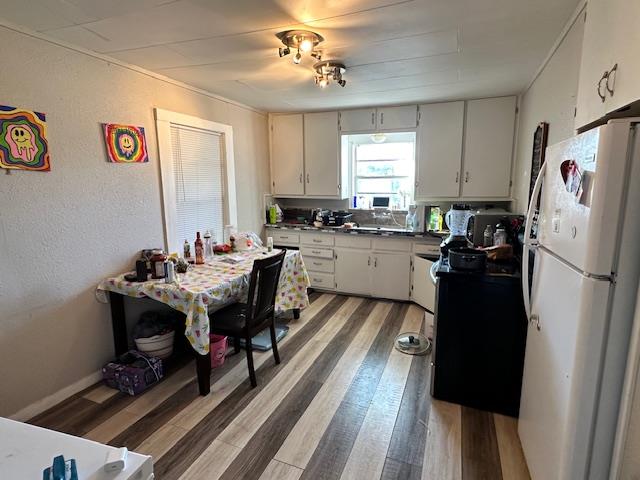 kitchen with hardwood / wood-style floors, white fridge, and white cabinets