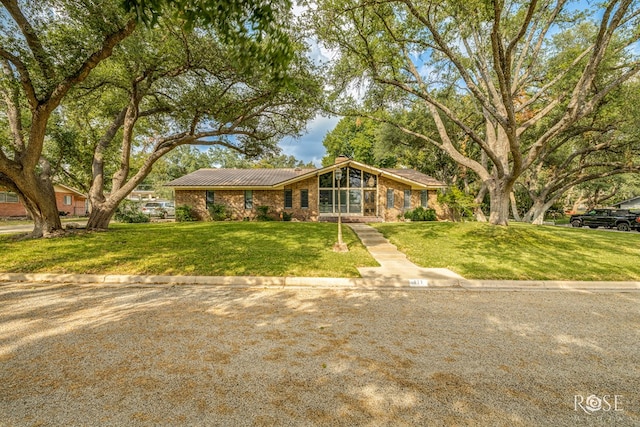 111 Manor St, Sonora, TX 76950 - mid-century modern home with a front lawn, brick siding, a chimney, and a metal roof