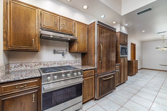 111 Manor St, Sonora, TX 76950 - kitchen with high end stove, under cabinet range hood, light tile patterned floors, black microwave, and light stone counters