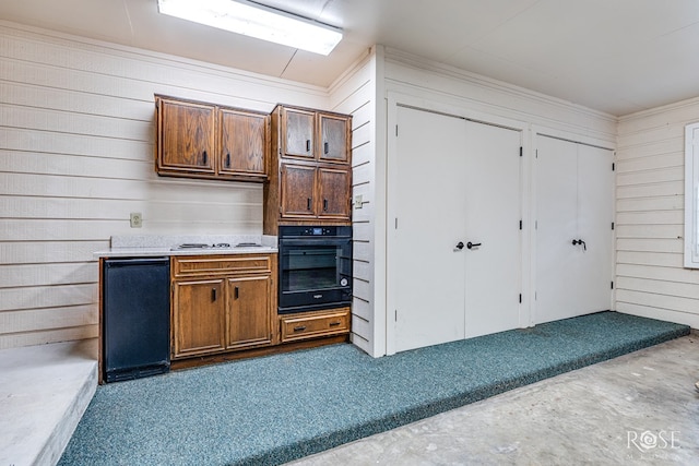 111 Manor St, Sonora, TX 76950 - kitchen featuring oven, light countertops, wooden walls, brown cabinets, and ornamental molding
