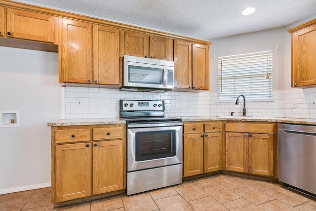 3622 Dominion Rdg, San Angelo, TX 76904 - kitchen with appliances with stainless steel finishes, a sink, light stone countertops, decorative backsplash, and a textured ceiling