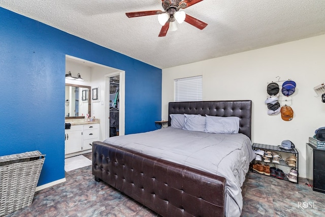 bedroom featuring a walk in closet, ensuite bath, a textured ceiling, a closet, and ceiling fan