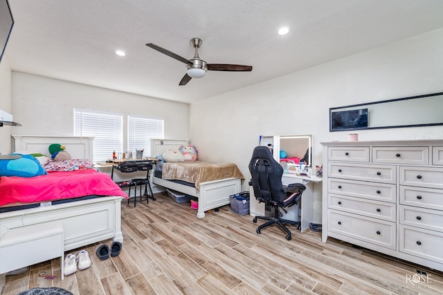 bedroom featuring ceiling fan, light hardwood / wood-style flooring, and a textured ceiling