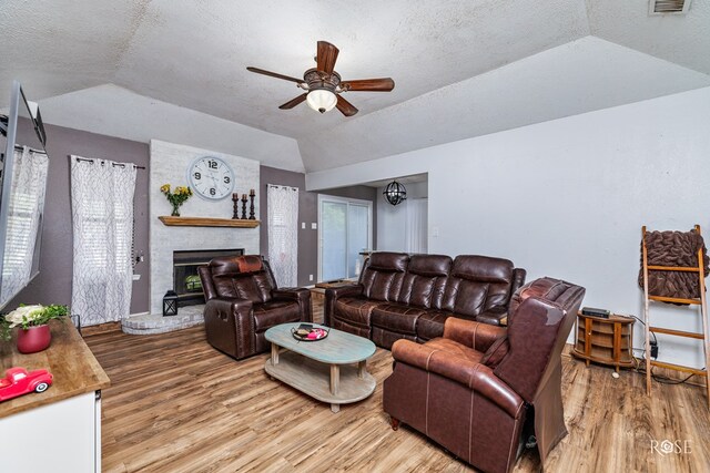 living room featuring lofted ceiling, a brick fireplace, hardwood / wood-style flooring, and ceiling fan