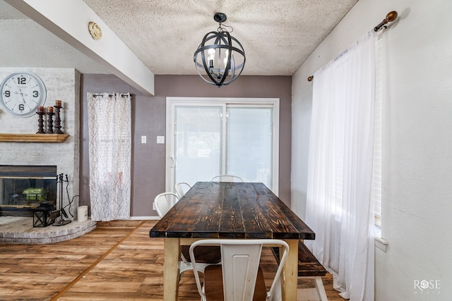 unfurnished dining area featuring a brick fireplace, a notable chandelier, hardwood / wood-style floors, and a textured ceiling