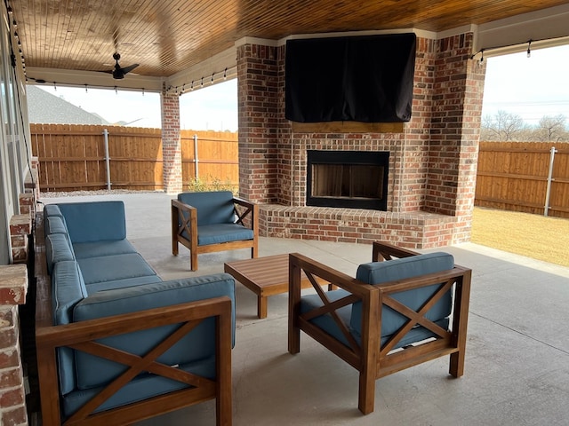 view of patio / terrace with ceiling fan, an outdoor living space with a fireplace, and fence