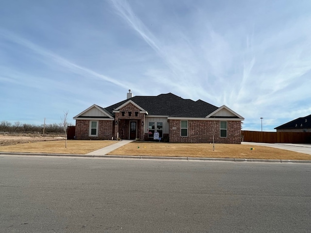 view of front of property featuring brick siding, fence, and a chimney