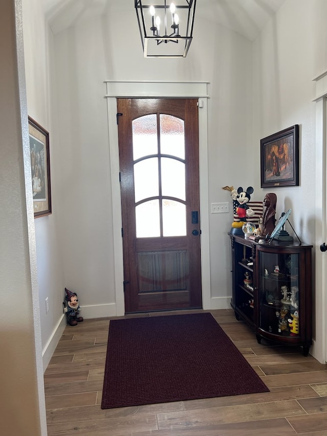 foyer with a notable chandelier, baseboards, and wood finished floors