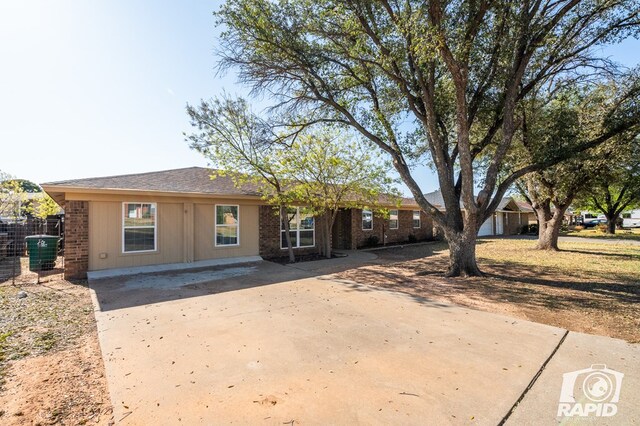 rear view of house with brick siding, central AC, a shingled roof, and driveway