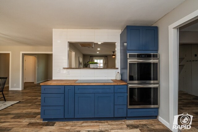 kitchen with butcher block counters, blue cabinets, black electric stovetop, and double oven