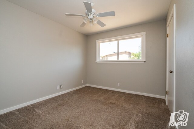 unfurnished room with dark colored carpet, baseboards, and ceiling fan