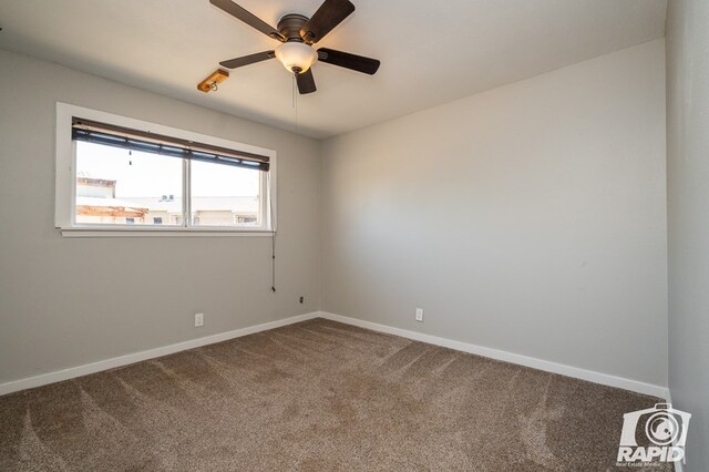 carpeted spare room with baseboards and a ceiling fan