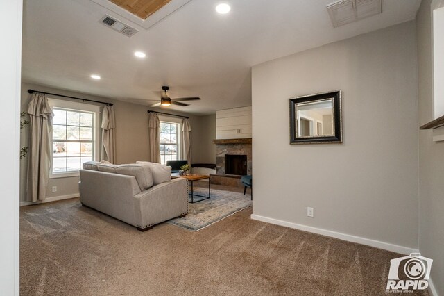 living room with a fireplace with raised hearth, baseboards, visible vents, and carpet floors