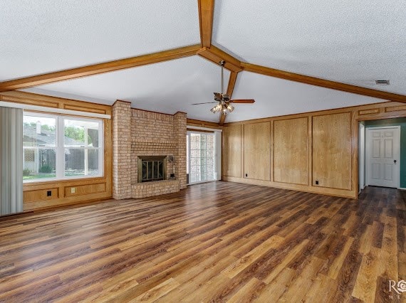 3309 Cedarhill Dr, San Angelo, TX 76904 - unfurnished living room featuring healthy amount of natural light, a ceiling fan, dark wood-style floors, a fireplace, and a textured ceiling