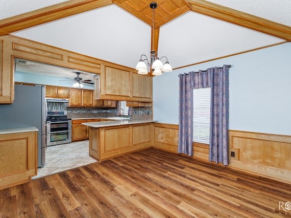3309 Cedarhill Dr, San Angelo, TX 76904 - kitchen featuring appliances with stainless steel finishes, a chandelier, light wood-type flooring, a peninsula, and vaulted ceiling