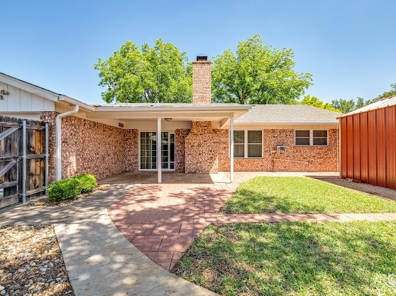 3309 Cedarhill Dr, San Angelo, TX 76904 - rear view of property with a chimney, brick siding, fence, a patio, and french doors