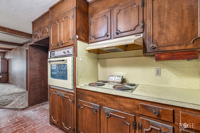1714 Shady Point Circle Dr, San Angelo, TX 76904 - kitchen featuring white appliances, light countertops, under cabinet range hood, a textured ceiling, and brick patterned floors