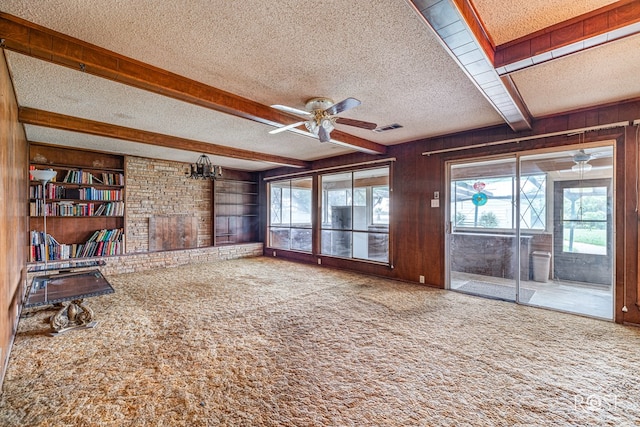 1714 Shady Point Circle Dr, San Angelo, TX 76904 - unfurnished living room featuring a ceiling fan, a textured ceiling, carpet flooring, beam ceiling, and wooden walls