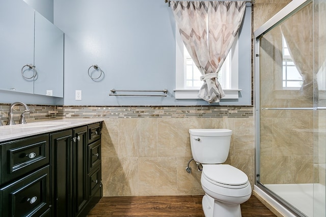 bathroom featuring tile walls, toilet, healthy amount of natural light, vanity, and a shower stall