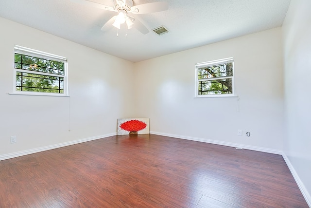 empty room with plenty of natural light, wood finished floors, baseboards, and ceiling fan