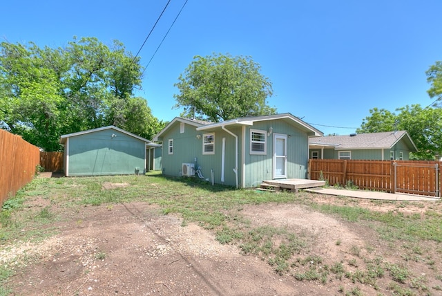 rear view of property with a fenced backyard and an outbuilding