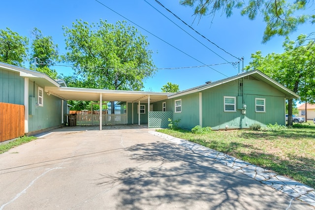 view of front of property with driveway, an attached carport, and fence