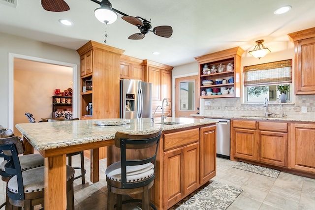 kitchen with sink, a center island with sink, appliances with stainless steel finishes, a kitchen breakfast bar, and decorative backsplash