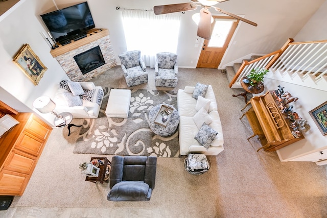 carpeted living room featuring ceiling fan and a fireplace