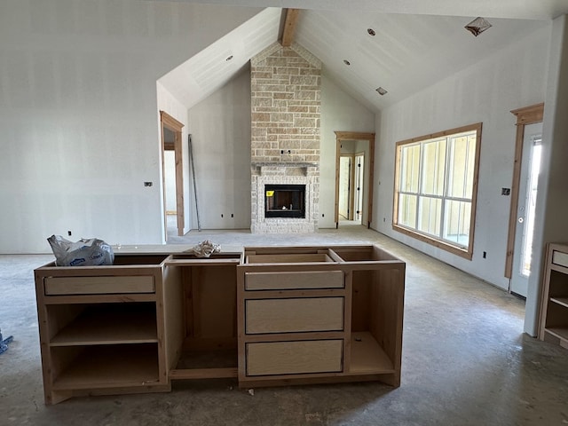 living room featuring beamed ceiling, high vaulted ceiling, and a stone fireplace