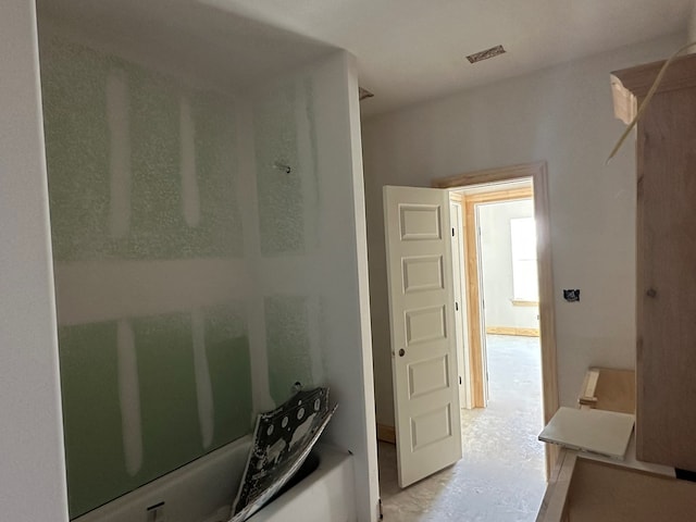 bathroom with washtub / shower combination and unfinished concrete flooring